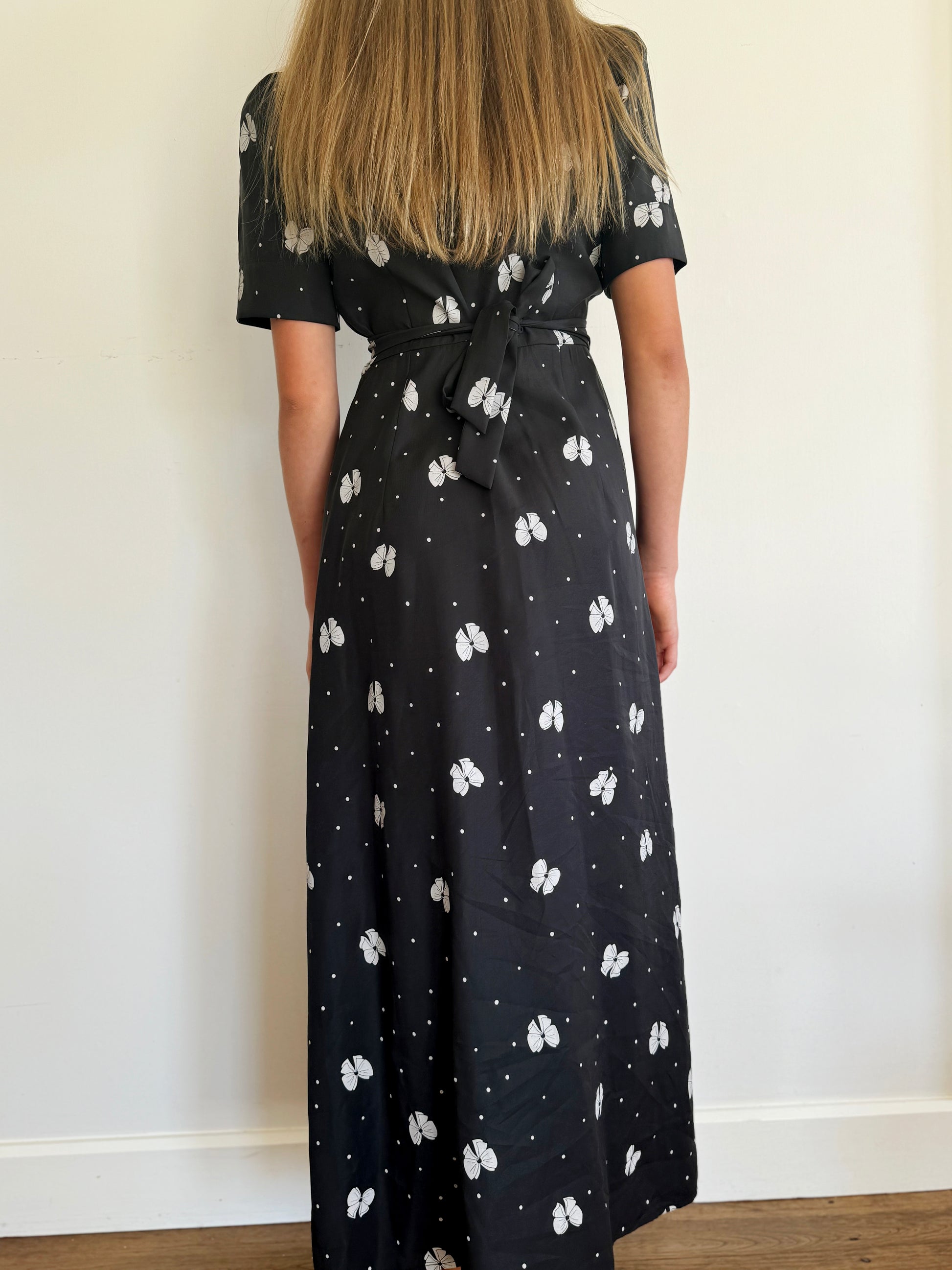 Back of wrap dress. Dress has a black backgound with white bow print.
