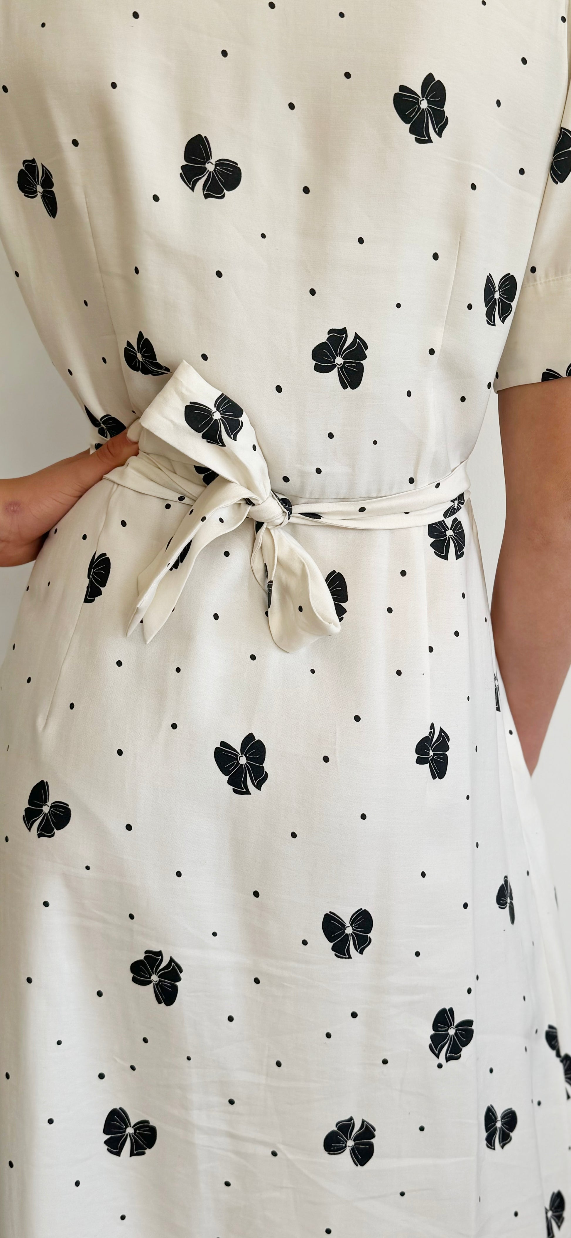 Close up shot of back tie detail of cream dress with black bows.