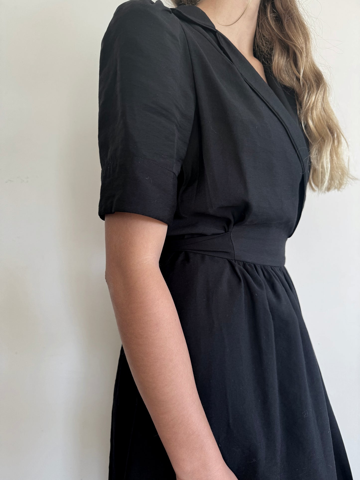 Side view of black wrap dress.