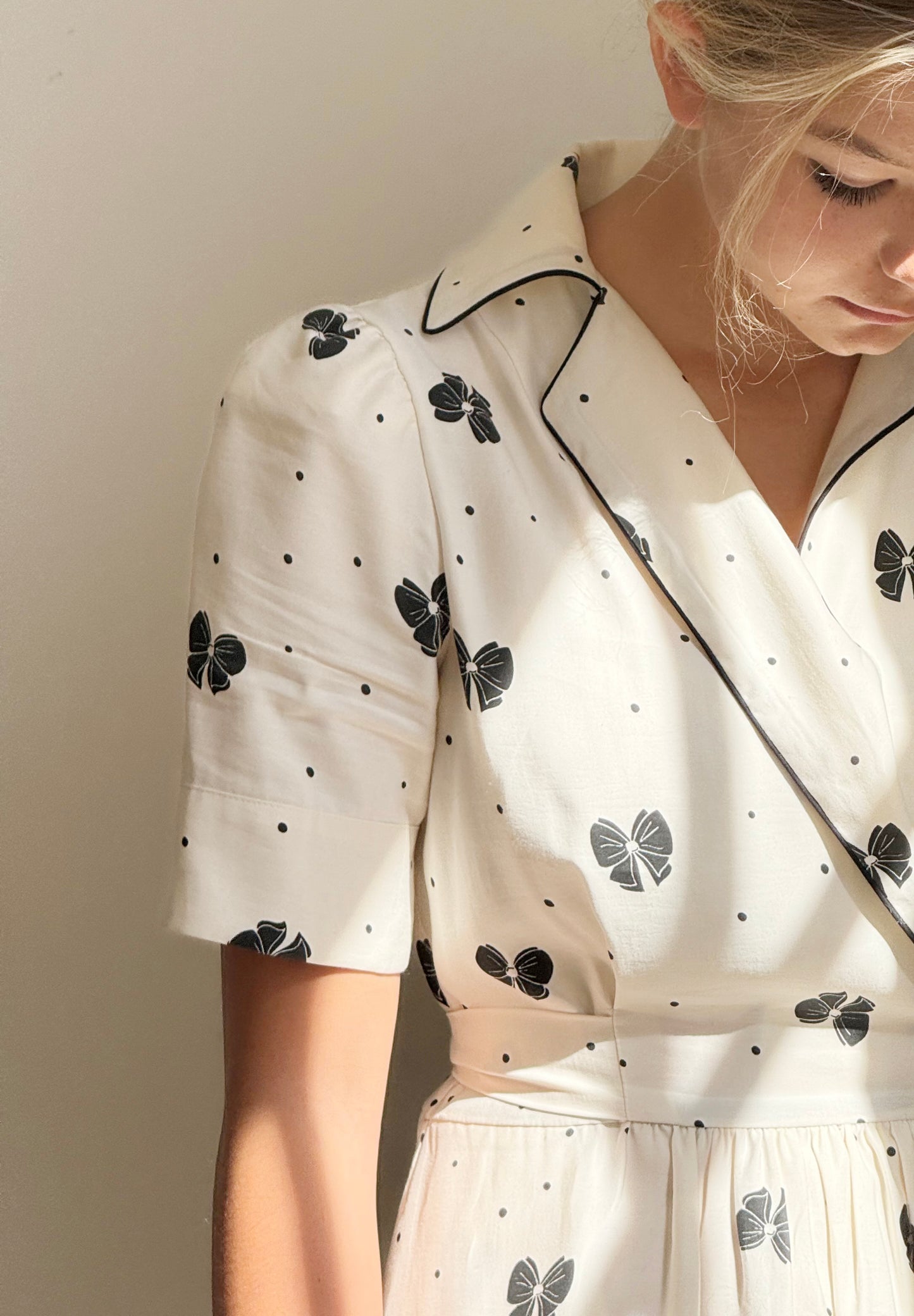 Close up shot of front detail of cream dress with black bows.