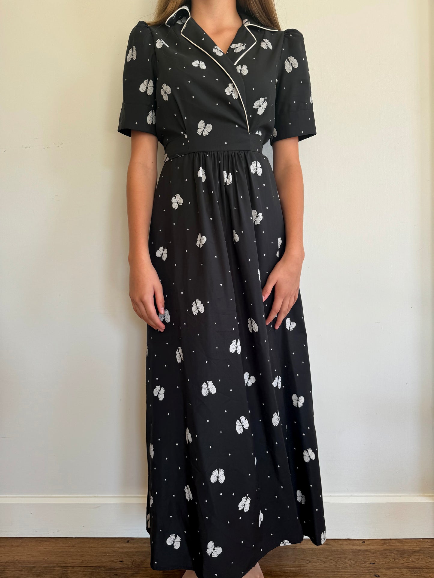 Front of wrap dress. Dress has a black backgound with white bow print.