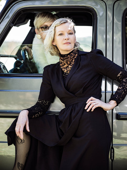 black wrap dress styled with leopard print and lace. Model posing in front of car.